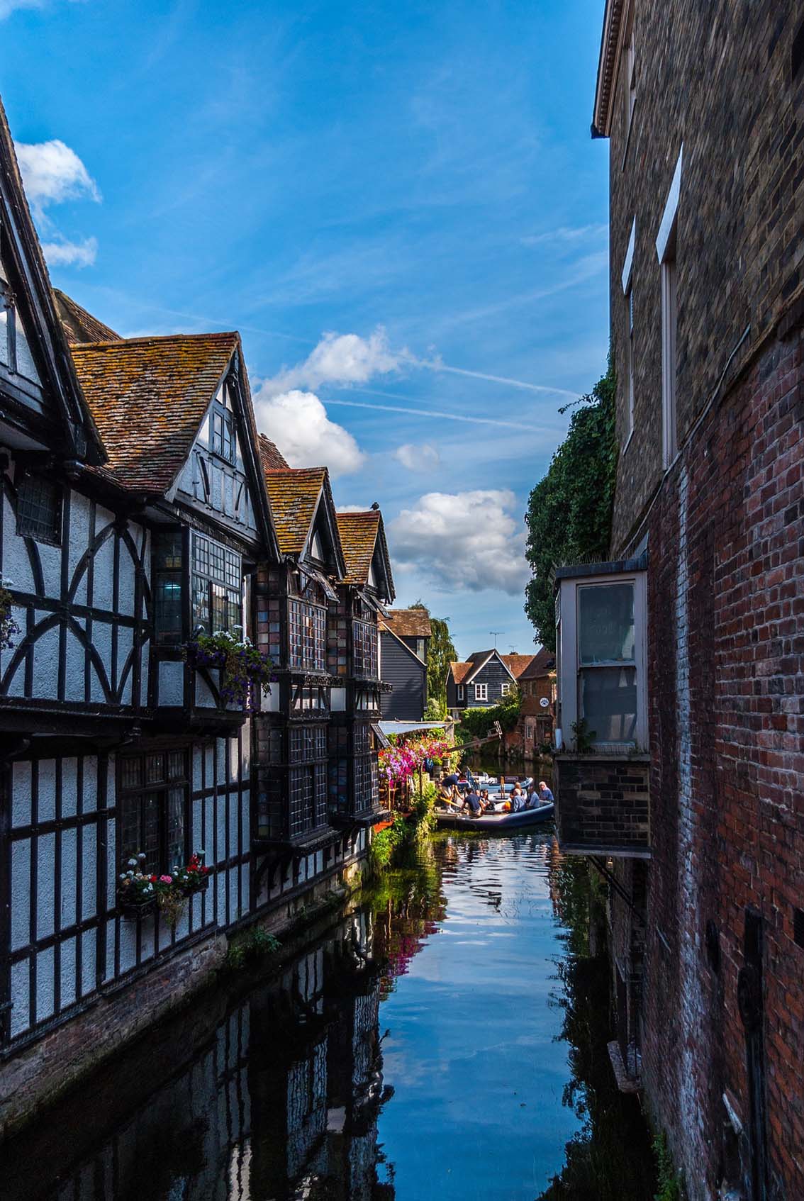 River view between old Tudor houses in Canterbury, with punting boats in the distance 