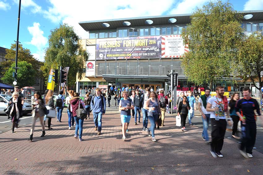 View of campus building with lots of people walking in front