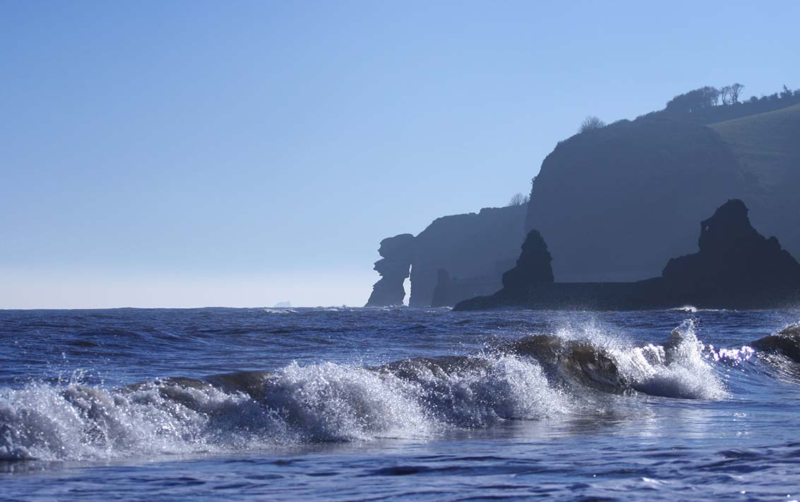 Ocean view from the shore with cliffs in the distance