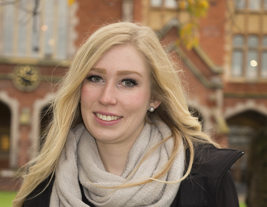 Headshot of Lauren smiling in front of a brick building