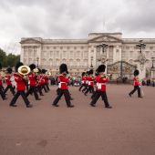 View of Buckingham Palace with guards marching in front with their brass instruments