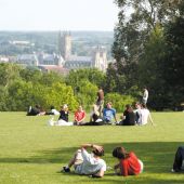 Students sitting on a green lawn with cathedral in the distance