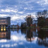 Dusk view of a lit up campus building beside silhouettes of trees