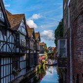River view between old Tudor houses in Canterbury, with punting boats in the distance 