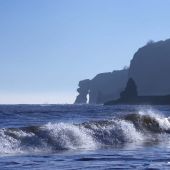 Ocean view from the shore with cliffs in the distance