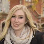 Headshot of Lauren smiling in front of a brick building